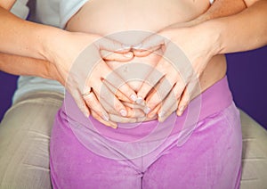 Expectant mother holding little heart. Pregnant Woman holding her hands in a heart shape on her baby bump. Pregnant