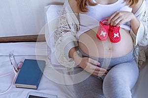 The expectant mother placed gift or red newborn shoes on her tummy after going for an ultrasound to determine the gender of her