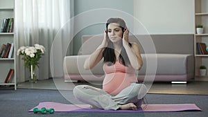 Expectant mother putting on headset and enjoying melodies calming her child