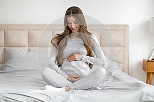 Expectant mother sitting on bed