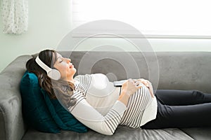 Expectant mother sleeping with music on the couch