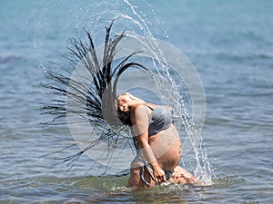 Expectant mother in striped bikini playing in water