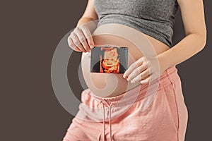 Expectant mother tenderly connects with her unborn child, holding ultrasound photo to her pregnant belly