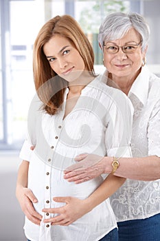 Expectant woman and senior mother smiling photo