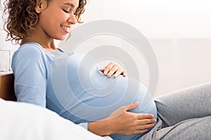 Expectation concept. Afro pregnant woman lying in bed
