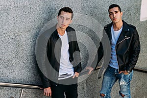 mans posing near railing. Handsome young mans in stylish black clothes and white shoes posing near a railing. friendship