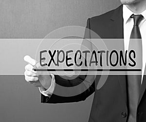 Expectations. Businessman in a suit with a marker writing on visual screen