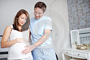 Expecting. A caring husband touching his wifes baby bump - Copyspace.