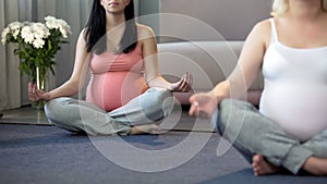 Expecting lady trainer giving yoga for pregnant women, preparing body for labour