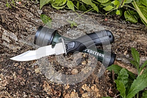 Expedition knife and flashlight waterproof on the tree trunk in the forest