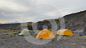 Expeditionary extreme tents of different colors stand in a small ravine on the lava fields of Kamchatka