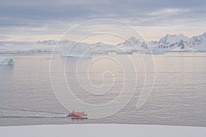 Expeditions - Zodiac with tourists cruises through Antarctic iceberg landscape at Portal Point