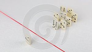 Expelled from the group, unable to cross the red line that separates them. Scene with group of domino. Concept of photo