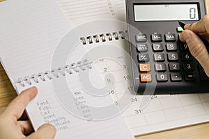 Expense, cost and payment calculation concept, female hand holding pen pushing buttons on calculator with expense list on notepad