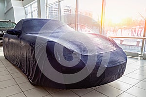 The expensive car in the box is carefully prepared for winter operation, covered with a professional cover made of blue special