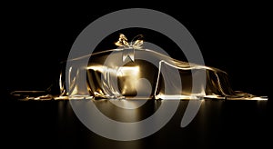 Expensive car gift covered by gold shiny fabric with bow-knot isolated on a black studio background.