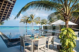 Expensive dining set up white chairs and table near swimming pool at the tropical outdoor restaurant at island luxury resort