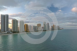 Expensive highrise hotels and condos over sandy beachfront on Atlantic ocean shore in Sunny Isles Beach city at sunset