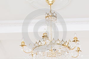 Expensive interior. Large electric chandelier made of transparent glass beads. White ceiling decorated with stucco