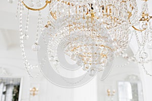 Expensive interior. Large electric chandelier made of transparent glass beads. White ceiling decorated with stucco