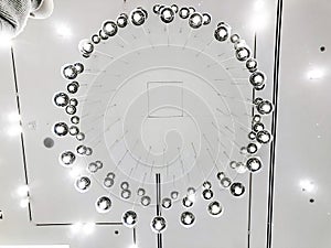 Expensive interior. Large electric chandelier made of transparent glass beads. White ceiling decorated with stucco molding.