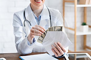 Expensive medicine. Smiling doctor counts money in envelope