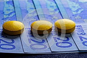 Expensive medicine treatment, tablets pills on 20 euro bills fan, macro image