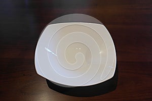 Expensive square shaped luxury porcelain plate on an oak table setting