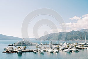 Expensive superyacht and motor yachts are moored to piers in the sea against the backdrop of mountains