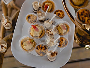 Expensively decorated table with tartlets and ice-cream in white utensils