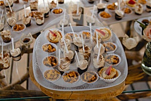 Expensively decorated table with tartlets and ice-cream in wooden utensils