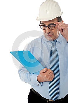 Experienced achitect in hardhat studying files. photo