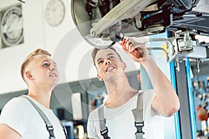 Experienced auto mechanic teaching an apprentice about disk brakes