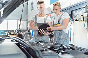 Experienced auto mechanic using a laptop for scanning engine errors