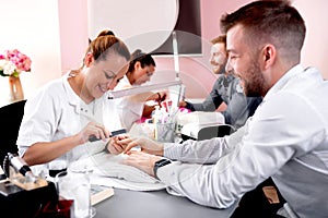 Experienced beauty salon worker handling her customer with a manicure treatment