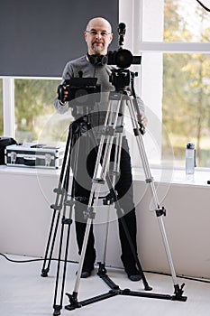 An experienced cameraman shoots a video in the studio. Man uses camera and tripods. Professional audio equpment