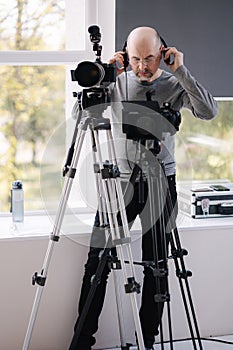 An experienced cameraman shoots a video in the studio. Man uses camera and tripods. Professional audio equpment