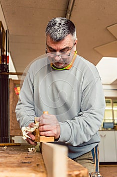 Experienced carpenter planing a board photo