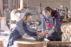 Experienced carpenter teaching young apprentice at workshop