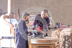 Experienced carpenter teaching young apprentice at workshop