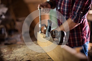 Experienced carpenter in work clothes and small business owner working in woodwork workshop, using sandpaper