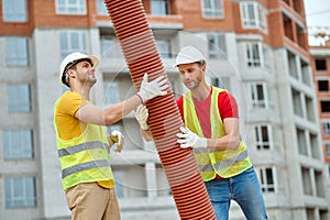 Experienced Caucasian workers in hardhats installing a drainage system