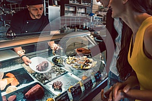 Experienced chef choosing raw seafood from the freezer for two customers