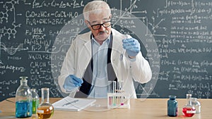 Experienced chemist doing chemical test then writing down results working in lab