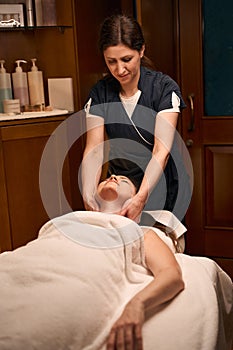 Experienced chiropractor treating adult woman for cervicalgia photo