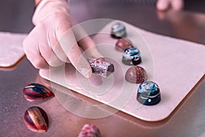 Experienced chocolatier holding sweet with silver coating photo