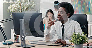 An experienced company employee dressed in a shirt and tie prepares documents on the computer, drafts an article or a
