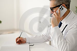 Experienced confident senior doctor with grey hair during phone call