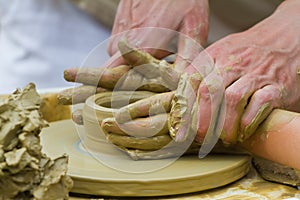 Experienced craftsman hands assist and help a child to form a clay bowl, ethnography lesson on traditional making of kitchen tools