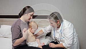 Experienced doctor checks body of cute newborn baby girl